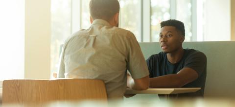 Two people talking across the table from each other.